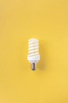 Energy saving light bulb on a yellow background. Economical consumption of electricity. The concept of nature conservation