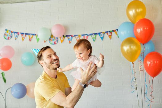 Happy father and baby daughter celebrating a birthday together at home