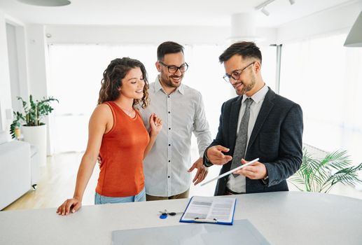 Young happy couple and an agent in a new property