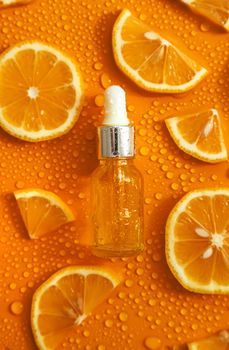 Bottle of cosmetics and drops of liquid, moisturizing orange. Hyaluronic acid. Selective focus. Spa.