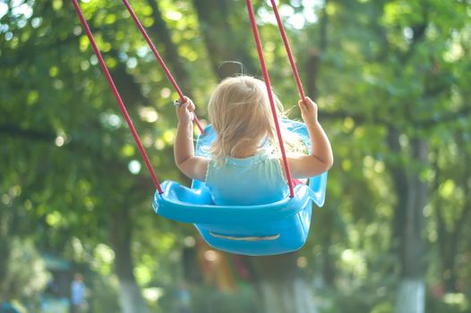 toddler girl on a swing in the park. High quality photo