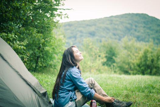 woman among the mountains near the tent enjoys nature. High quality photo