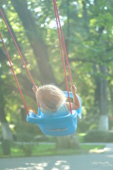 toddler girl on a swing in the park. High quality photo