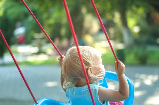 toddler girl on a swing in the park. High quality photo