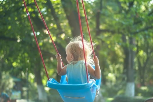 toddler girl on a swing in the park. High quality photo