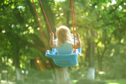 toddler girl on a swing in the park. High quality photo