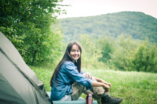 woman among the mountains near the tent enjoys nature. High quality photo