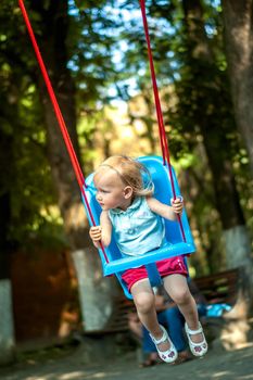 toddler girl on a swing in the park. High quality photo