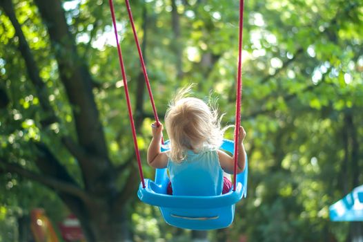 toddler girl on a swing in the park. High quality photo