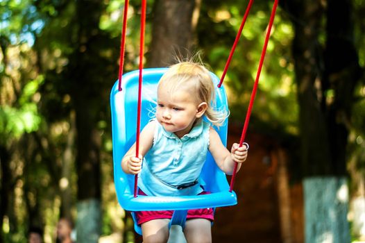 toddler girl on a swing in the park. High quality photo