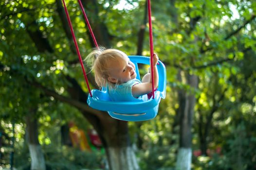 toddler girl on a swing in the park. High quality photo