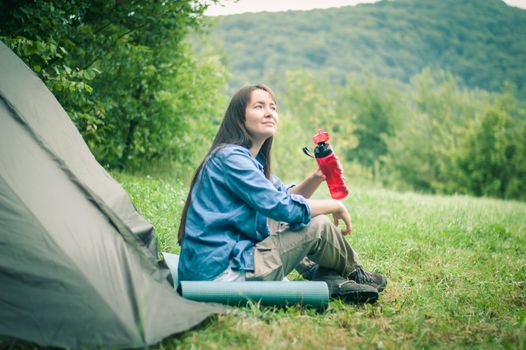 woman among the mountains near the tent enjoys nature. High quality photo