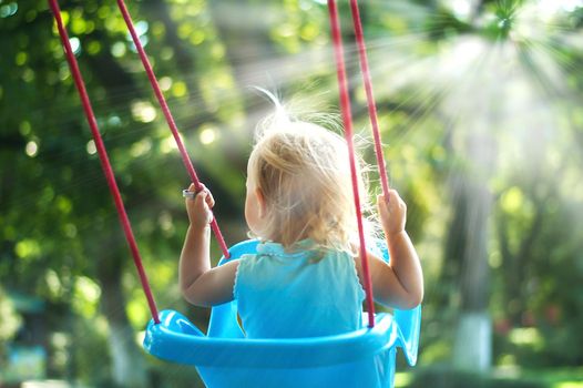 toddler girl on a swing in the park. High quality photo