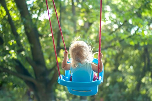 toddler girl on a swing in the park. High quality photo