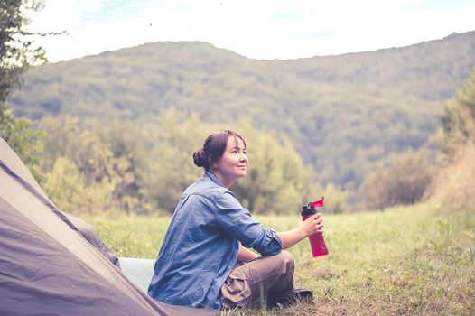 woman among the mountains near the tent enjoys nature. High quality photo