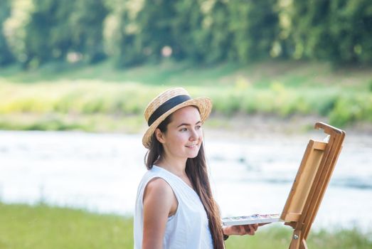 beautiful girl artist outdoor with wooden aesel and watercolor