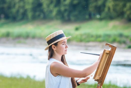 beautiful girl artist outdoor with wooden aesel and watercolor