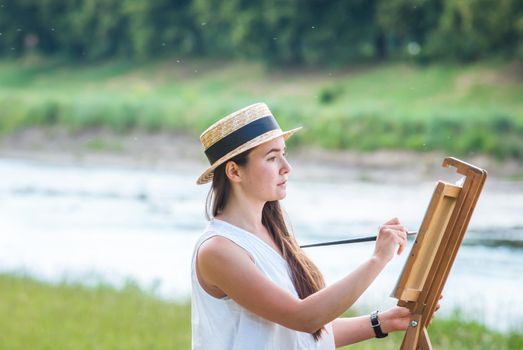 beautiful girl artist outdoor with wooden aesel and watercolor