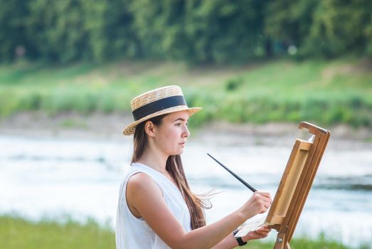 beautiful girl artist outdoor with wooden aesel and watercolor