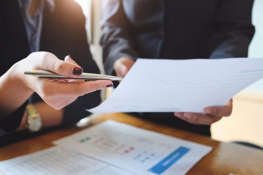 An auditor holds a pen pointing to documents to examine budgets and financial fraud