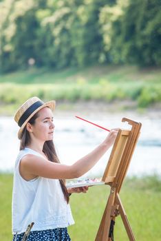 beautiful girl artist outdoor with wooden aesel and watercolor