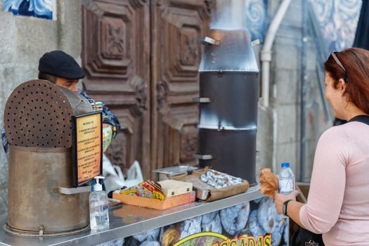 Porto, Portugal - October 23, 2020: Street vendor of hot chestnuts cooked over charcoal installed in the historic city center on an autumn day