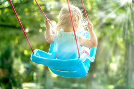 toddler girl on a swing in the park. High quality photo