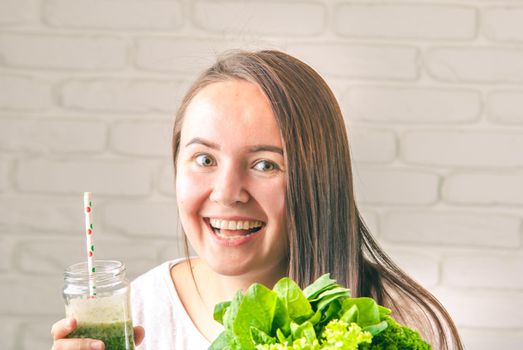 beautiful young smiling woman is drinking green detox shake . High quality photo