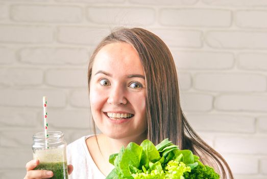 beautiful young smiling woman is drinking green detox shake . High quality photo