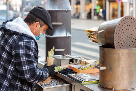 Porto, Portugal - October 23, 2020: Street vendor of hot chestnuts cooked over charcoal installed in the historic city center on an autumn day