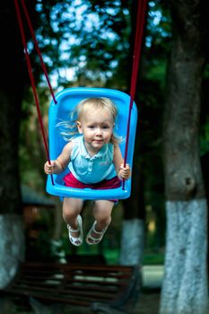 toddler girl on a swing in the park. High quality photo