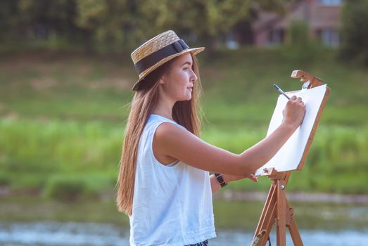 beautiful girl artist outdoor with wooden aesel and watercolor