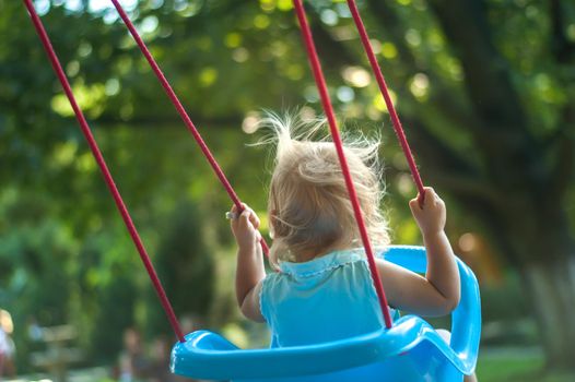 toddler girl on a swing in the park. High quality photo