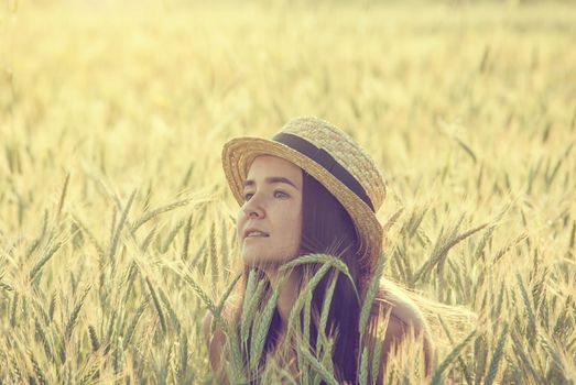 young woman in straw hat in the middle of wheat field