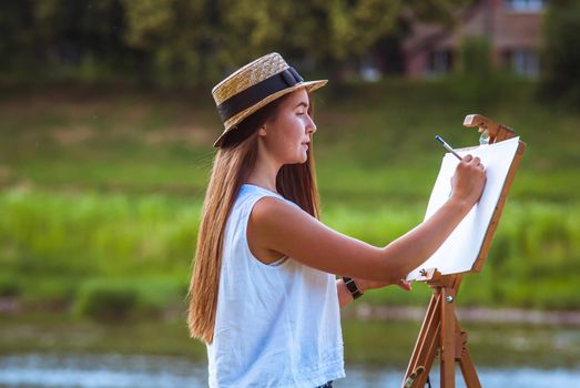 beautiful girl artist outdoor with wooden aesel and watercolor