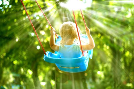 toddler girl on a swing in the park. High quality photo