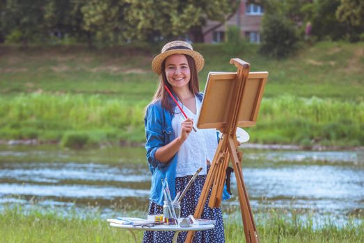 beautiful girl artist outdoor with wooden aesel and watercolor