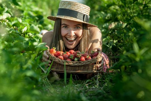girl in strawberrry field with basket of fresh picked fruits