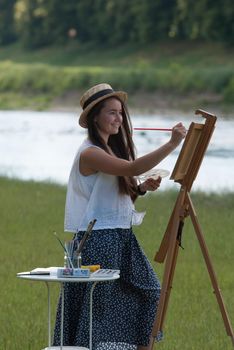 beautiful girl artist outdoor with wooden aesel and watercolor