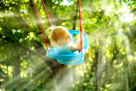 toddler girl on a swing in the park. High quality photo