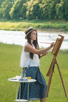 beautiful girl artist outdoor with wooden aesel and watercolor