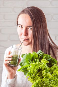 beautiful young smiling woman is drinking green detox shake . High quality photo