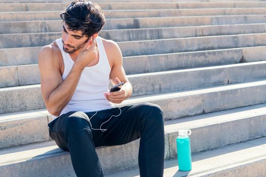 sporty man puts on earphones to listen to music during training, urban sport concept and healthy lifestyle, copy space for text