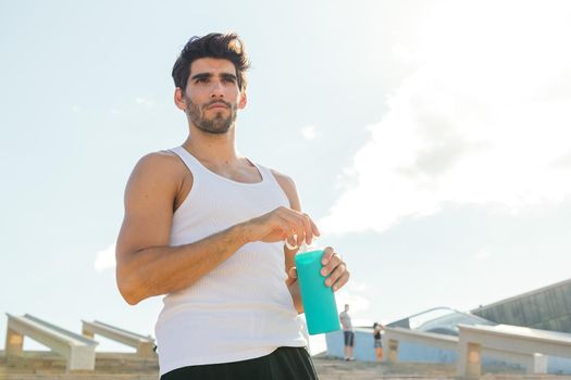 handsome sportsman with a bottle of water in a break from his training, concept of urban sport and healthy lifestyle, copy space for text