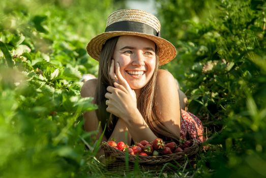 girl in strawberrry field with basket of fresh picked fruits