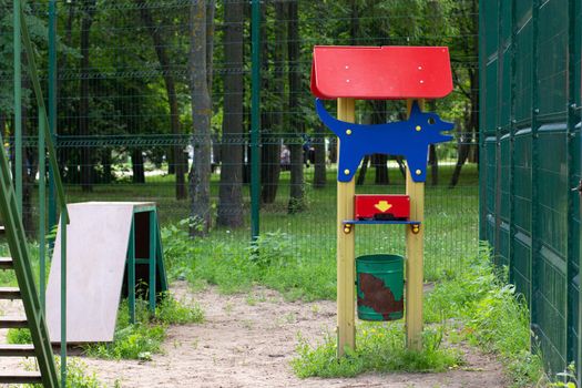 Colorful wooden dog waste station in dog park. Concept cleaning after dog
