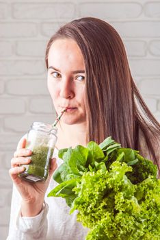 beautiful young smiling woman is drinking green detox shake . High quality photo