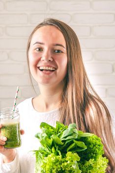 beautiful young smiling woman is drinking green detox shake . High quality photo