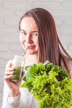 beautiful young smiling woman is drinking green detox shake . High quality photo