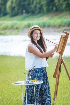 beautiful girl artist outdoor with wooden aesel and watercolor